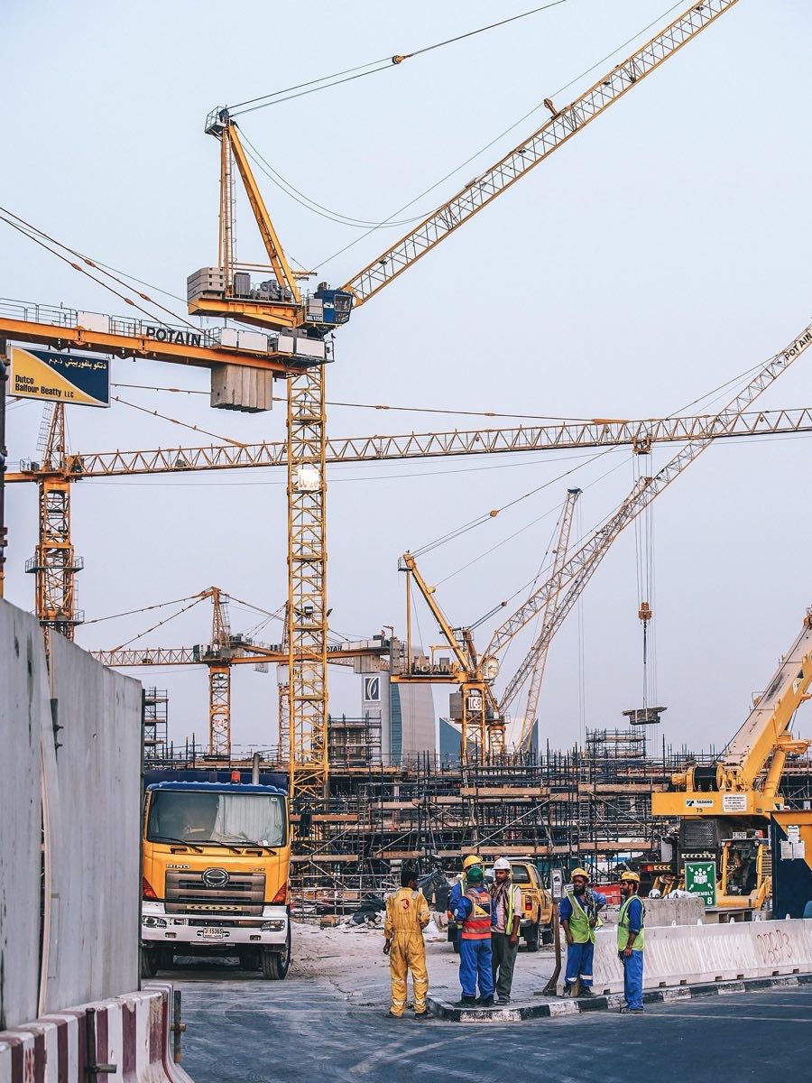 Site team in hard hats and hi-vis on a construction site with tower cranes