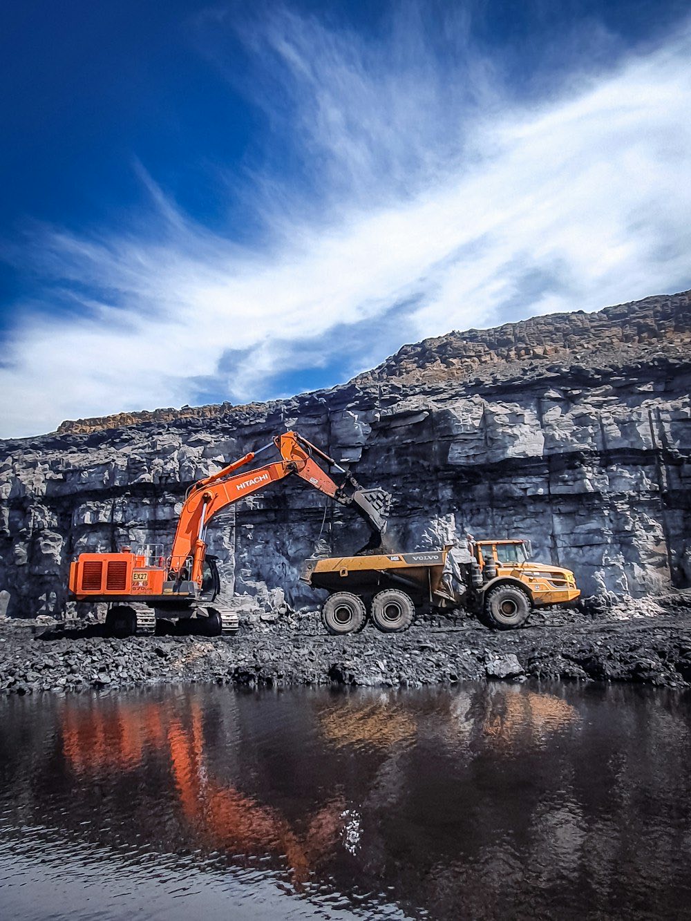 Excavator loading a dump truck at a rock face