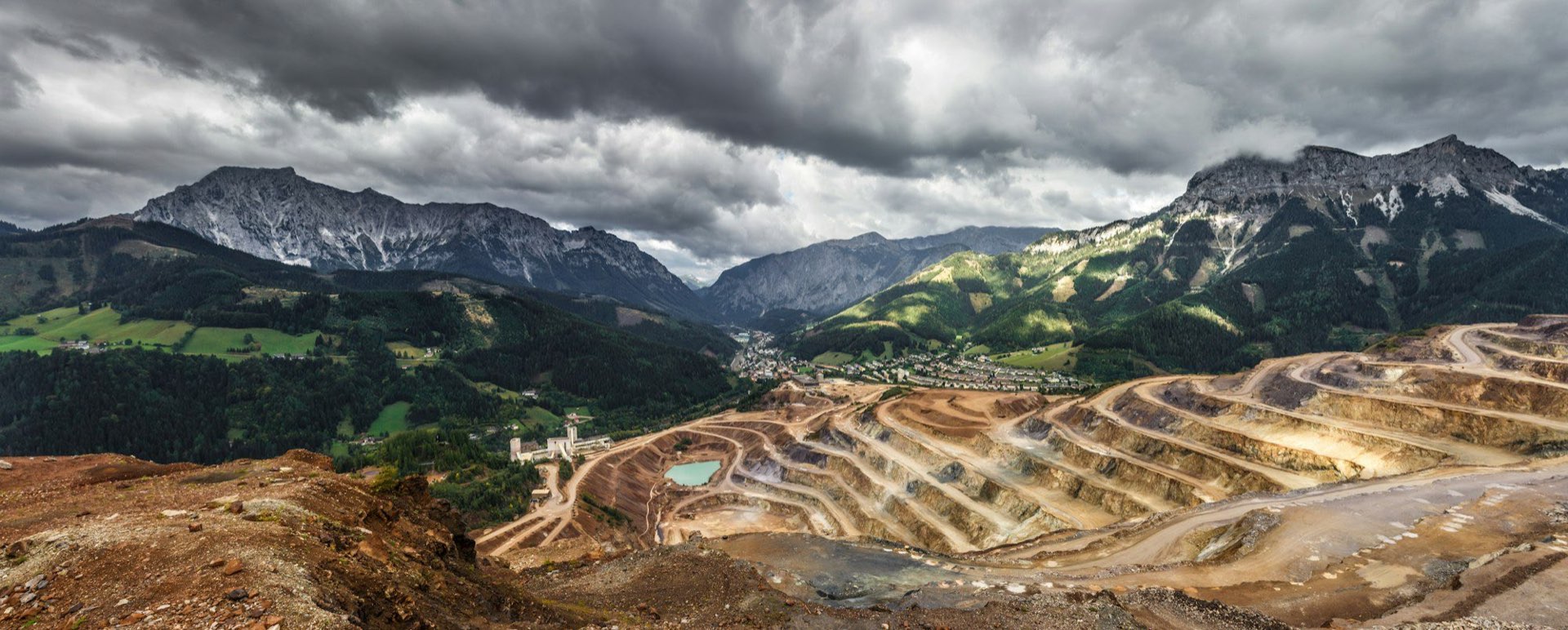 Open-pit mine terraces below a mountain range